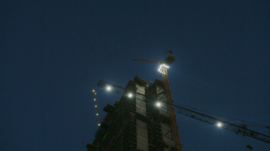 Canteiro contínuo com estrutura metálica iluminada à noite — torres metálicas e solares